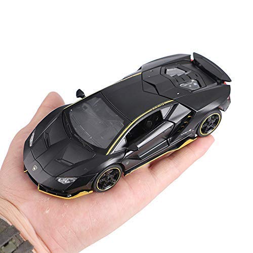Black and gold toy car held in a hand against a white background