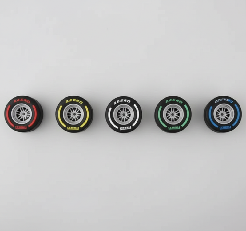 Five small tire models with different branding on a metallic surface