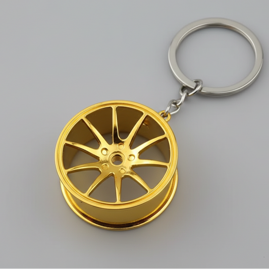 Gold car wheel rim keychain on a dark background