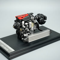 Model of a car engine on a black stand with a gray background